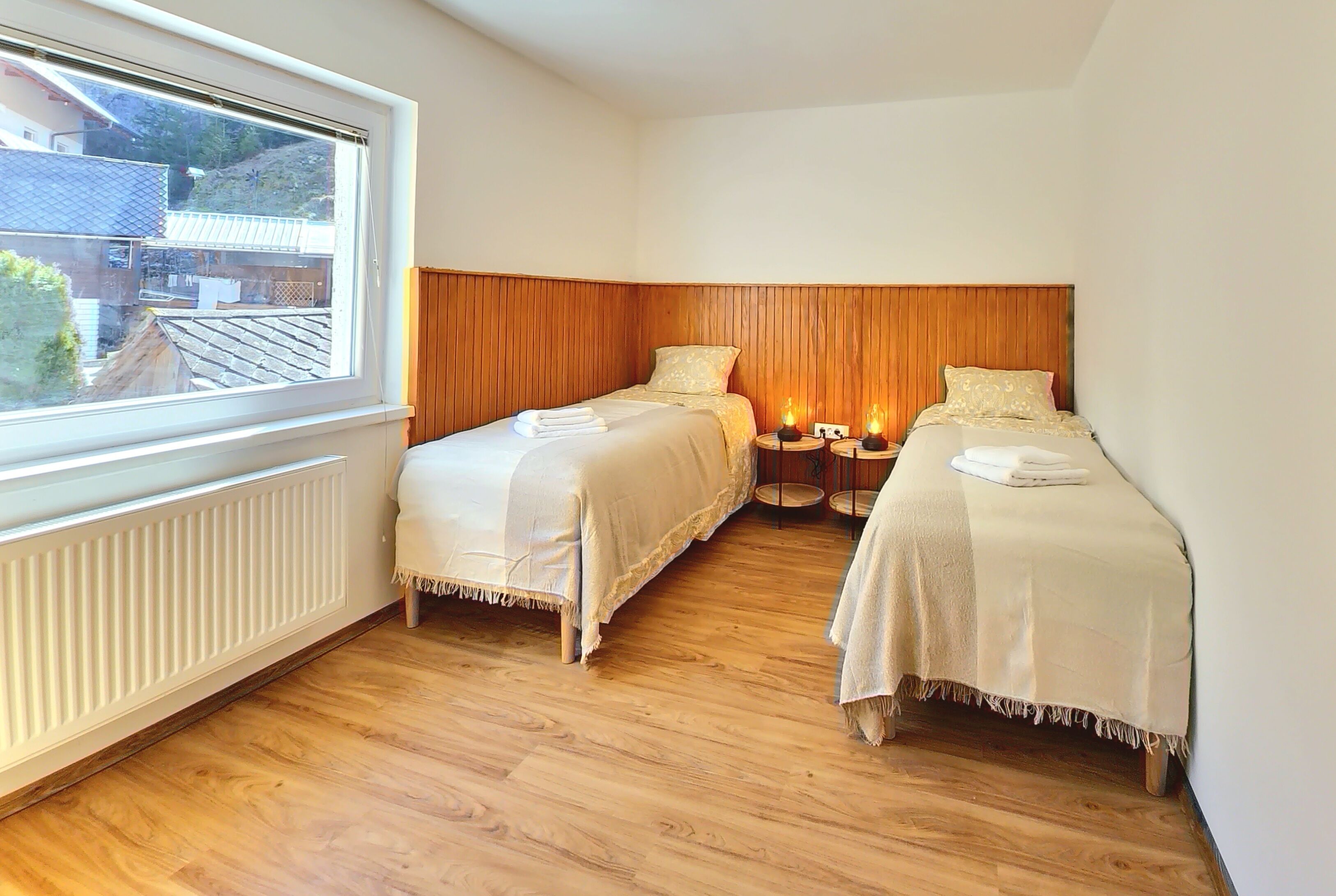 A bedroom with two beds, a window, and a radiator.