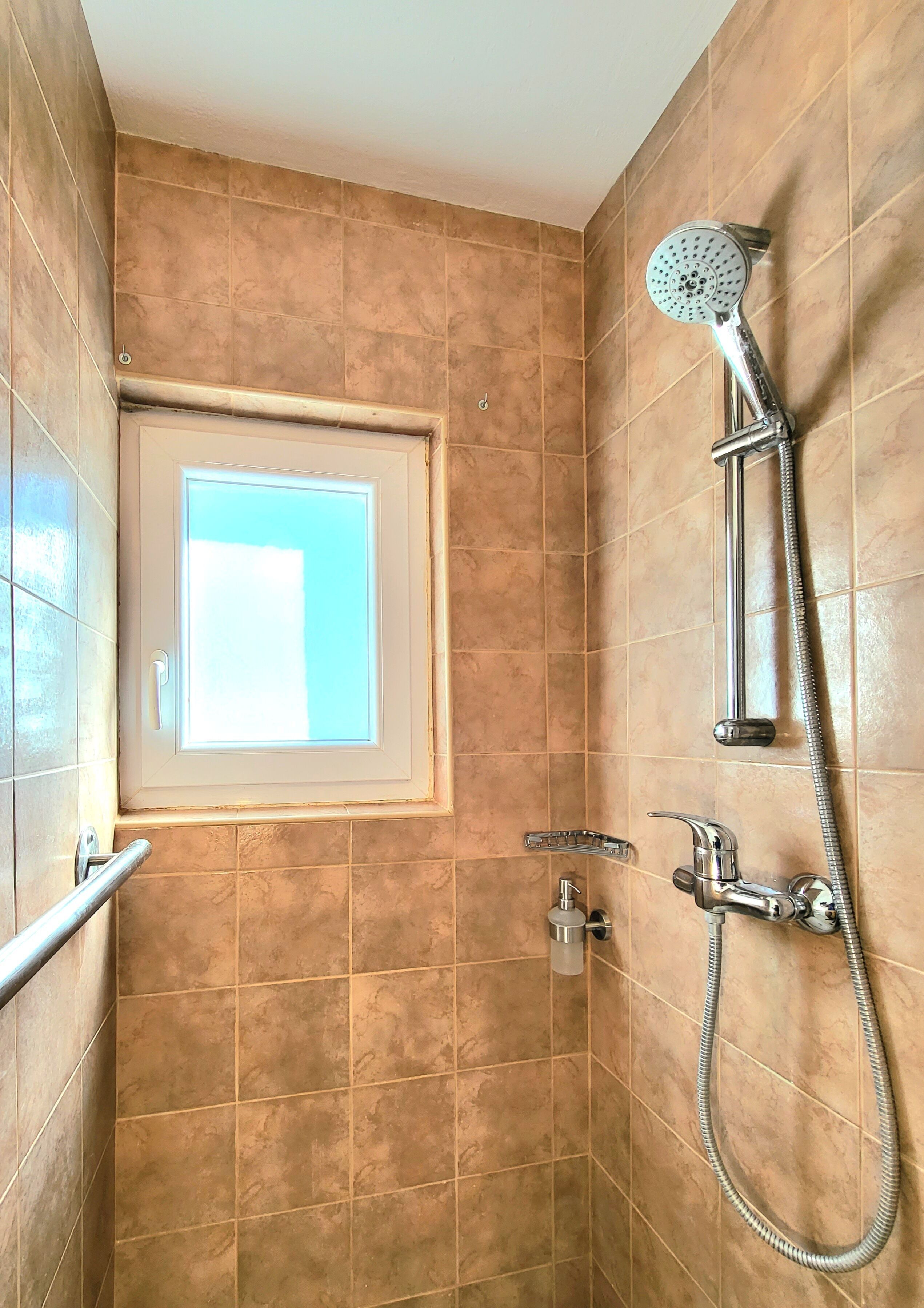 A shower with a handheld showerhead and a handheld faucet.
