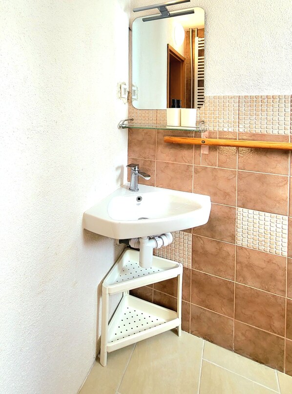 Un baño con lavamanos blanco, un espejo y un perchero para toallas.