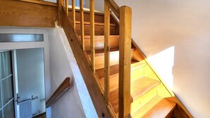 Una escalera de madera con barandilla que da a un rellano.