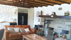 A cozy living room with a wooden ceiling, a stone fireplace, a leather sofa, and a coffee table. - Traditional Irish cottage with views of Slieve Patrick (Downpatrick)