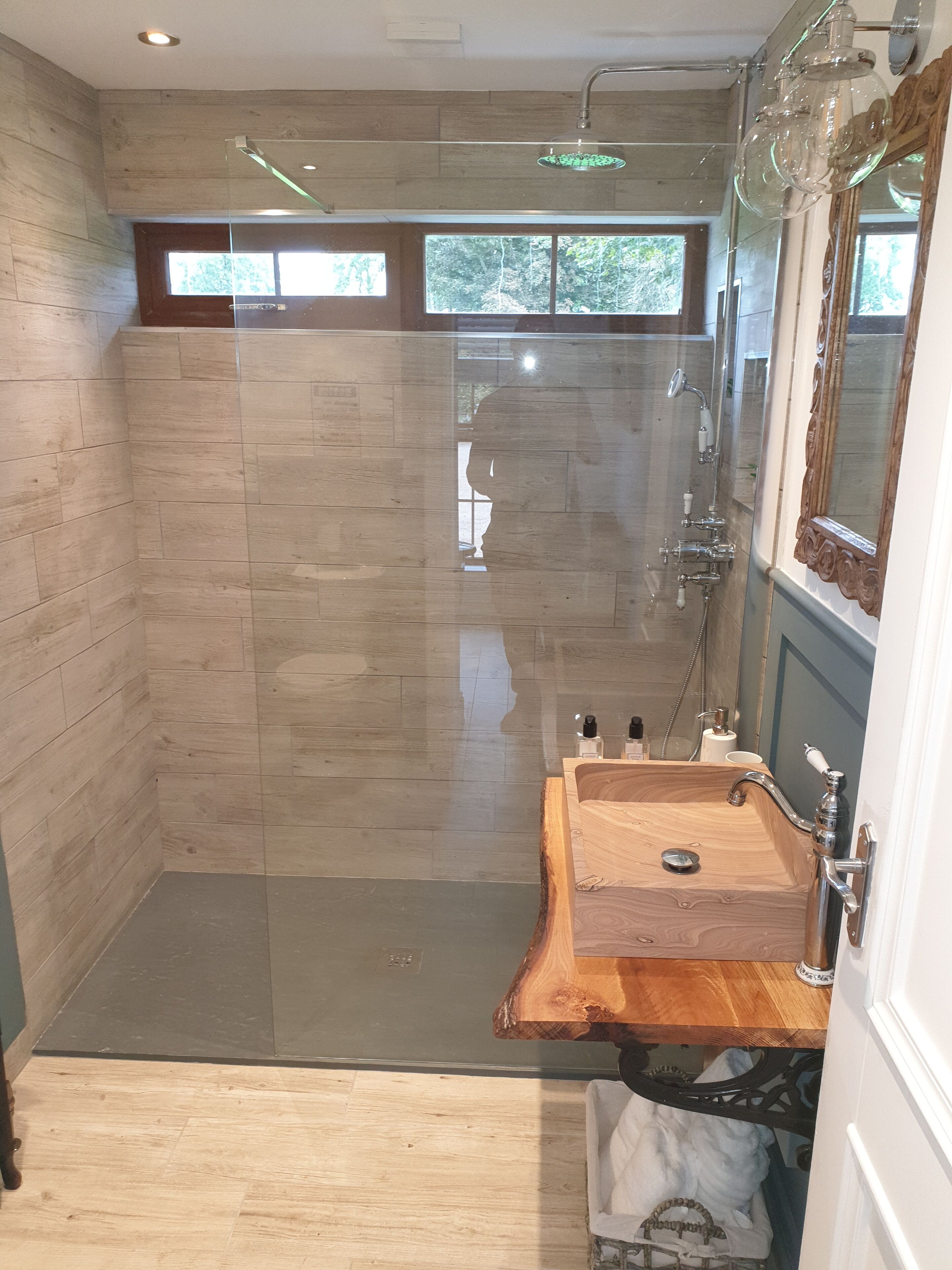Un baño moderno con ducha de vidrio, tocador de madera y un espejo grande.
