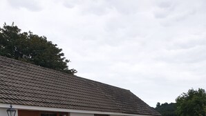 A house with a tiled roof, a front door, and a patio area with outdoor furniture. - Traditional Irish cottage with views of Slieve Patrick (Downpatrick)