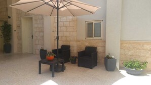An outdoor seating area with a table and chairs, surrounded by potted plants. - Aida Guest House (Nazareth)
