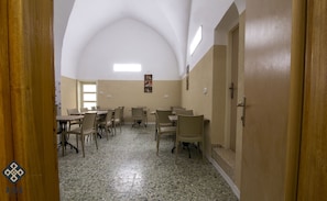 A conference room with a high arched ceiling, tiled floor, and several tables and chairs. - Aida Guest House (Nazareth)