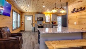 Una cocina moderna con paredes de madera, encimeras de granito y una isla central.