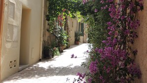 A narrow alleyway with a brick pathway, flanked by buildings with white walls and blue shutters. - Le Pêcheur Revisité by Winkyhouse Cassis (Cassis)