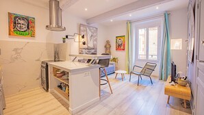 A modern kitchen with a central island, built-in oven, and a dining area with a chair and table. - Le Pêcheur Revisité by Winkyhouse Cassis (Cassis)