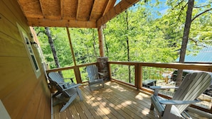 Une terrasse en bois avec deux fauteuils Adirondack et une cheminée en pierre.