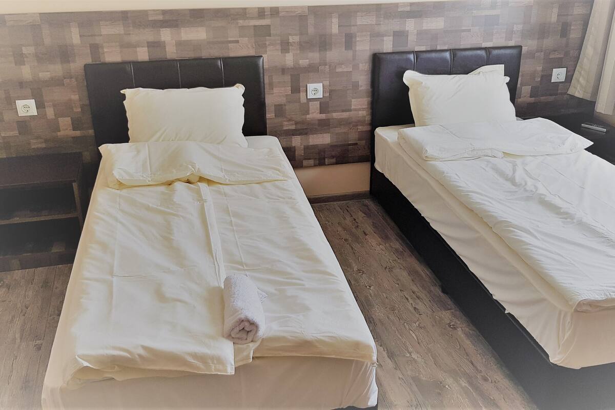 Two single beds with headboards, a wooden floor, and a wall with a patterned design.