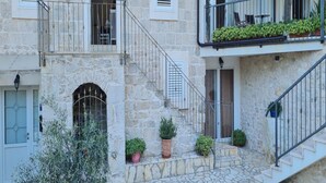 A stone building with a staircase leading to a balcony with potted plants. - Holiday Home Mico with Swimming Pool (Drvenik)