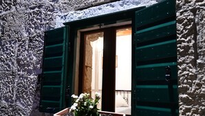 A window with green shutters, a wooden door, and a flower box with white flowers. - Apartment Rural Podastrana (Sinj)