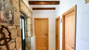 A hallway with a stone wall, wooden door, and a wooden floor. - Apartment Rural Podastrana (Sinj)