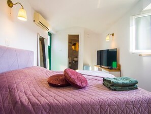 Un dormitorio con una cama grande, un televisor y una ventana.