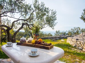 Una mesa con vista al mar, un muro de piedra y un árbol.