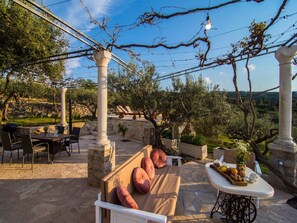 Un espacio al aire libre con pilares de piedra, una mesa con una exhibición de frutas y vistas al campo.