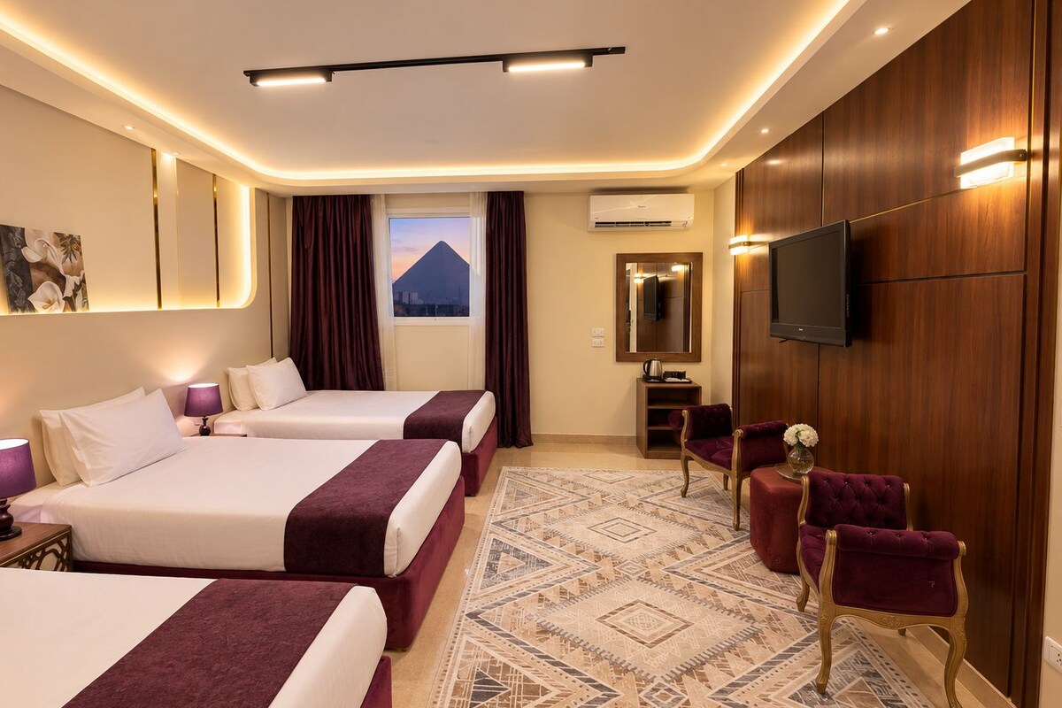 Een hotelkamer met twee bedden, een grote spiegel, een flatscreen televisie en uitzicht op een berg door het raam.