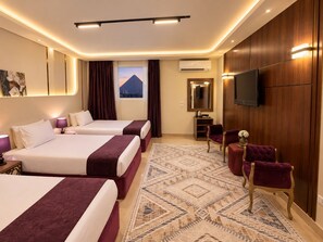 Habitación de hotel con dos camas, un espejo grande, un televisor de pantalla plana y vista a la montaña desde la ventana.