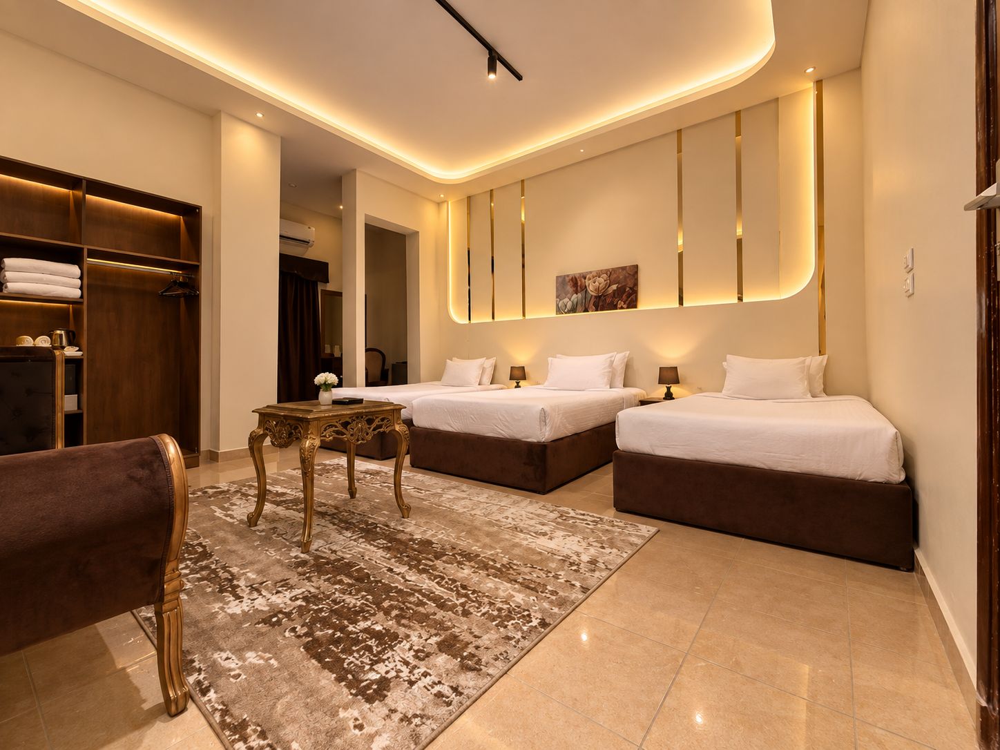 A modern hotel room with a large bed, a seating area, and a wardrobe.