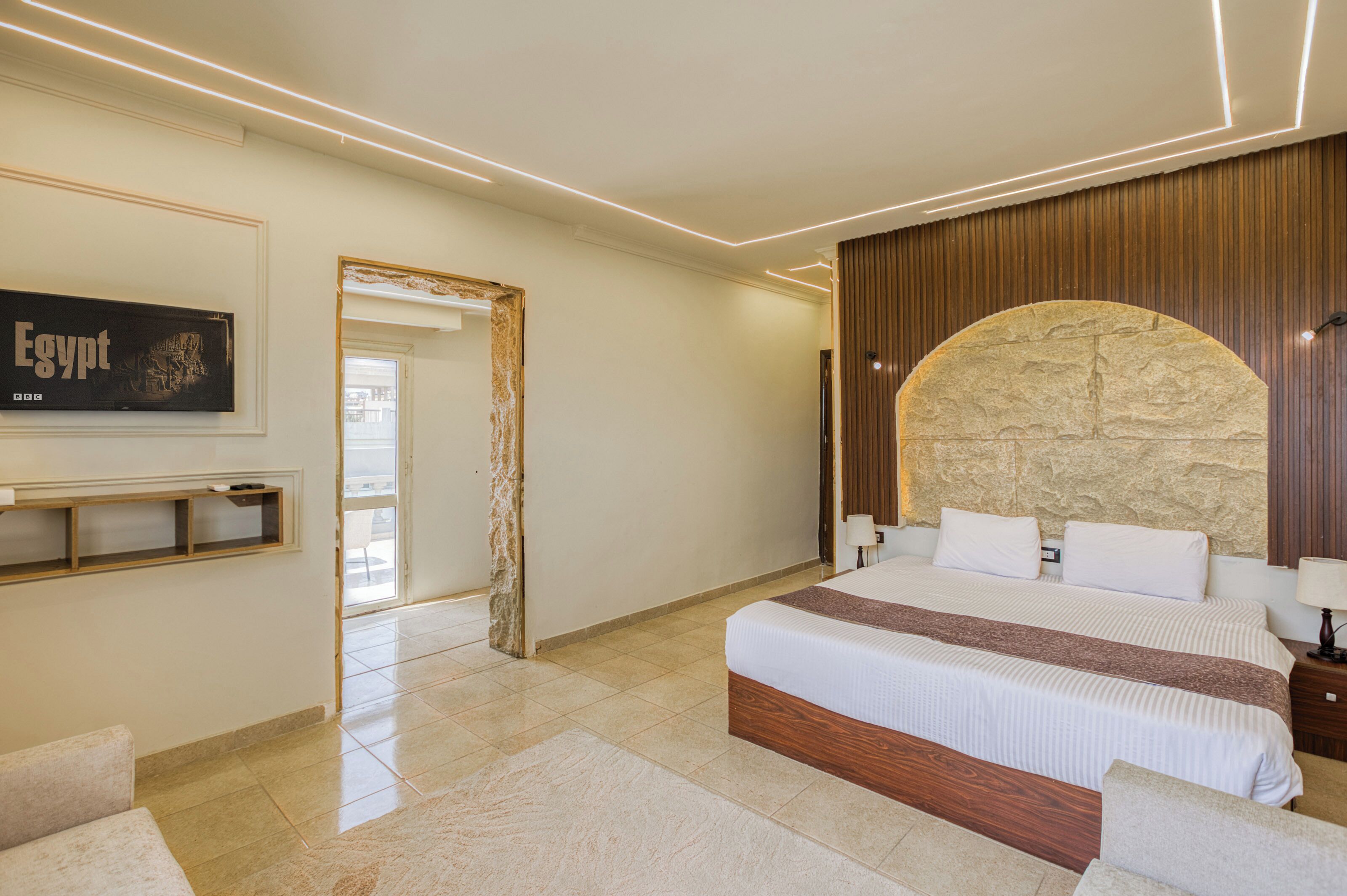 A modern bedroom with a large bed, a stone accent wall, a mounted artwork, and a wooden panel wall.