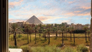 A view of the Great Pyramid of Giza with surrounding buildings and palm trees. - King Cheops Inn (Giza)