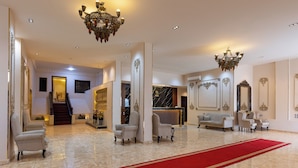 A spacious lobby with a red carpet, elegant chandeliers, and a reception desk. - King Cheops Inn (Giza)