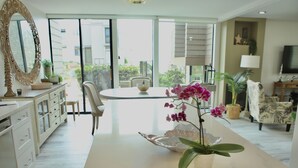 A modern kitchen with a central island, a dining area with a round table, and a view through large sliding glass doors. - Quiet Townhome with Ocean View (Solana Beach)