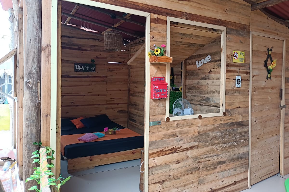 A wooden cabin with a bed, a small table, and a window.