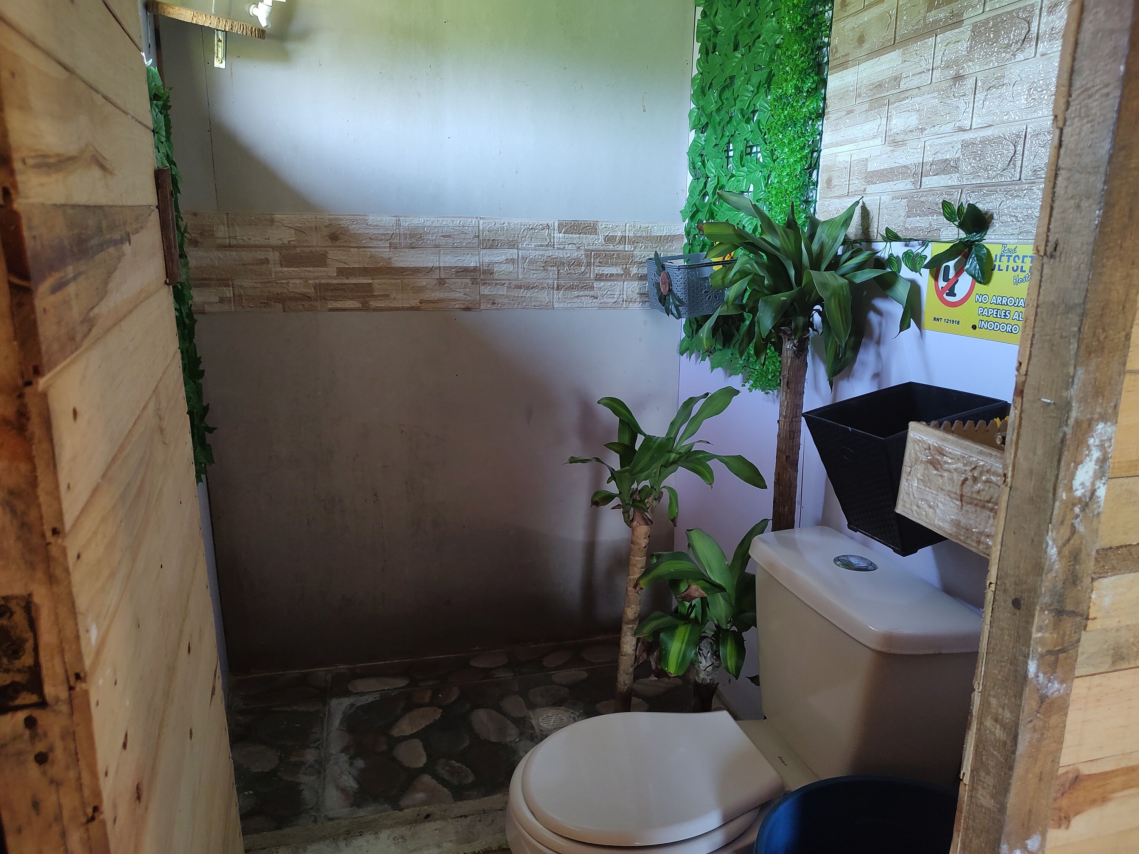 A small, rustic bathroom with a toilet, a sink, and a shower area.