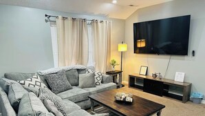 A living room with a sectional sofa, a coffee table, a TV, and a lamp. - The Great Escape, King suite, Kid friendly (Sevierville)