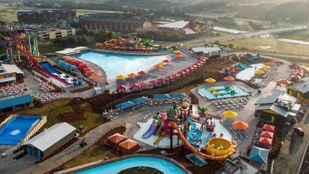 A water park with multiple slides and pools, surrounded by buildings and a parking area. - The Great Escape, King suite, Kid friendly (Sevierville)