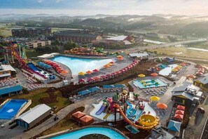 A water park with multiple slides and pools, surrounded by buildings and a parking area.