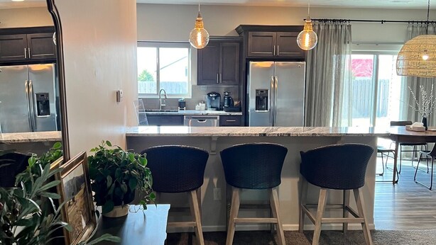 A modern kitchen with dark cabinets, stainless steel appliances, and a central island with bar stools.