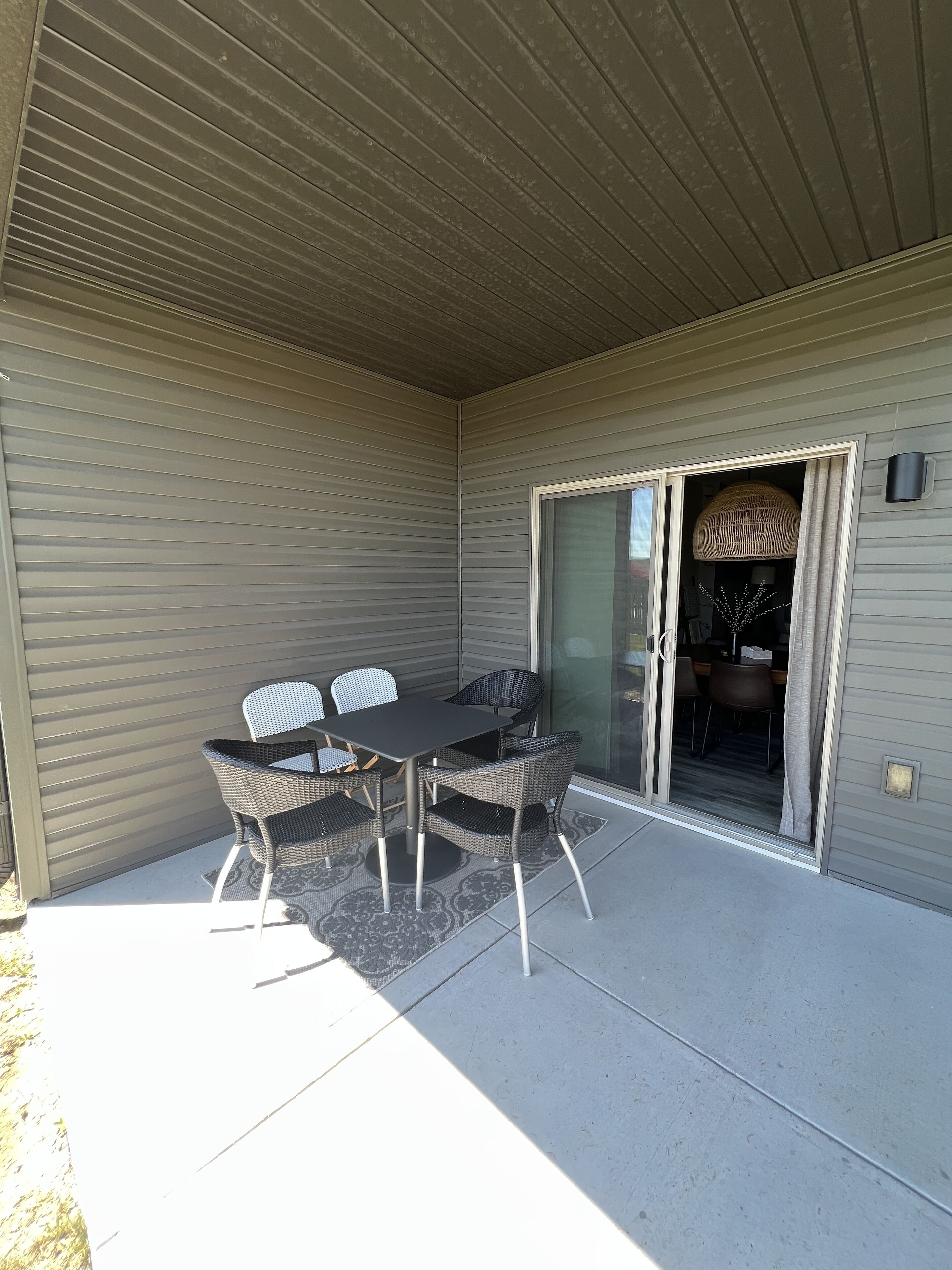A covered patio with a table and chairs, a sliding glass door, and a ceiling fan.