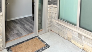 A modern entryway with a sliding glass door, a stone accent wall, and a doormat.