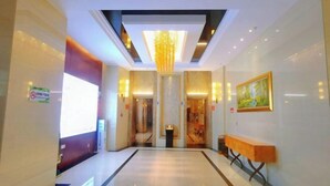 A hotel lobby with a modern chandelier, a reception desk, and a painting on the wall. - Jindu Hotel (Longnan)