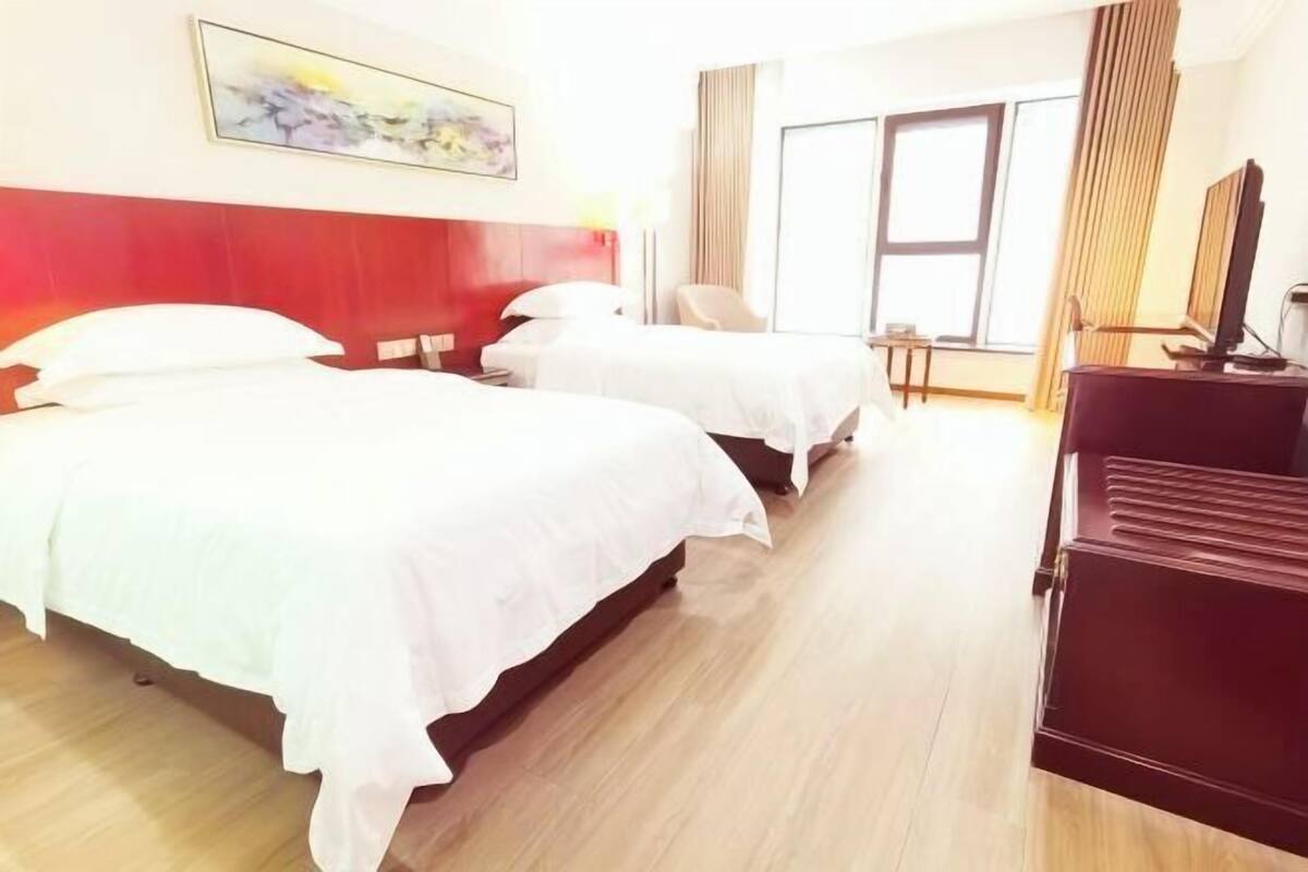 A hotel room with two beds, a TV, and a desk.