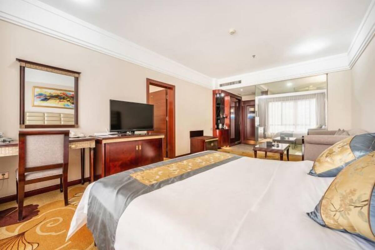 A hotel room with a bed, desk, television, and a seating area with a sofa and coffee table.