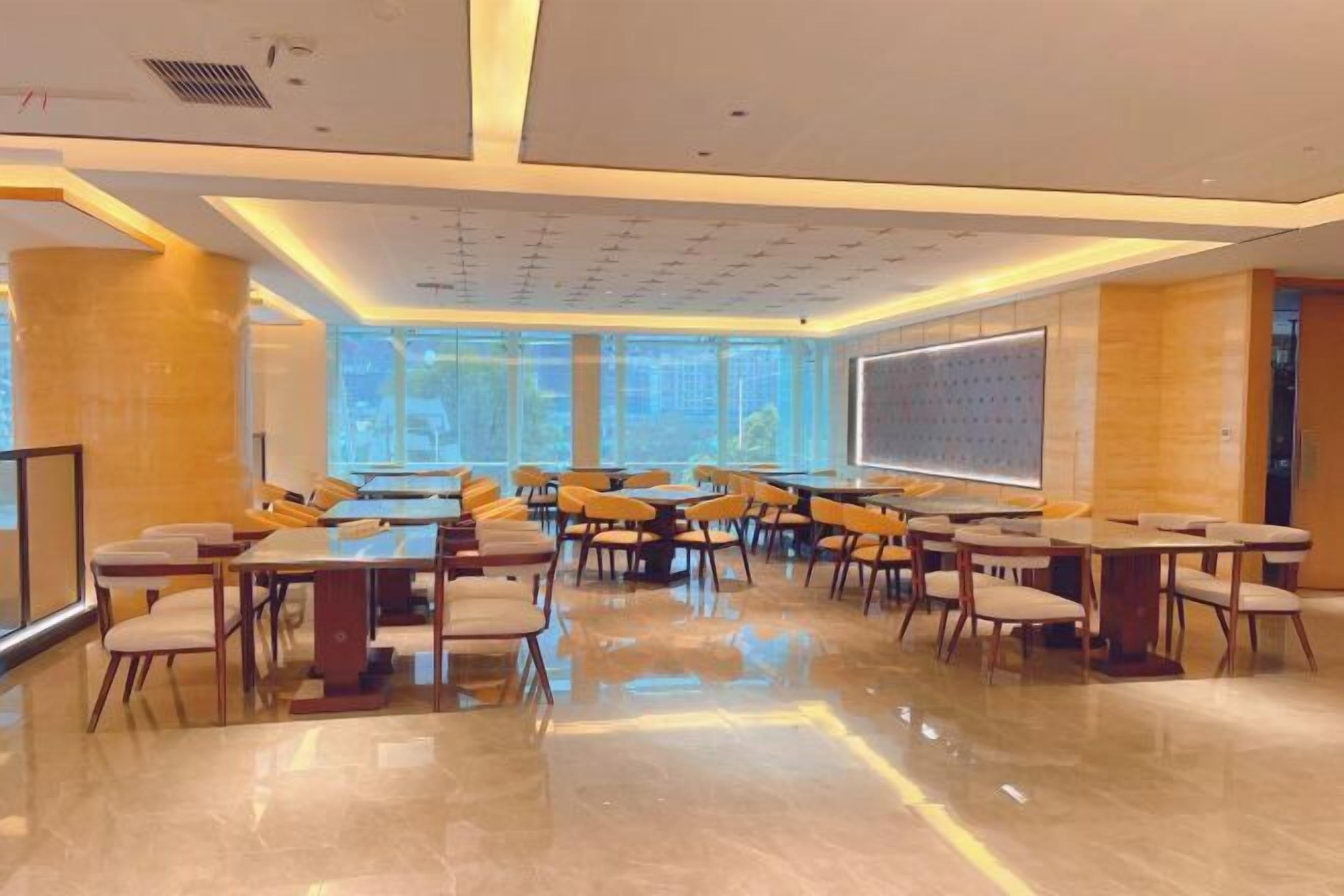 A spacious conference room with multiple tables and chairs, large windows, and a projection screen.