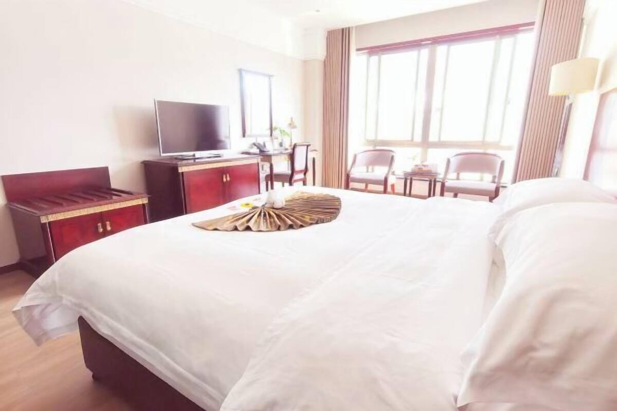 A hotel room with a large bed, a television, a desk, and two chairs.