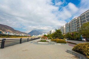 A paved walkway with a circular garden, modern buildings, and a mountain in the background. - Jindu Hotel (Longnan)