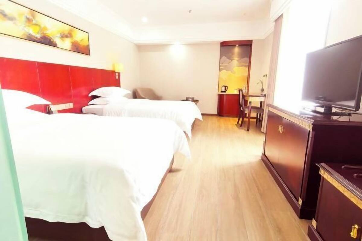 A hotel room with two beds, a TV, a desk, and a chair.