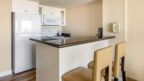 A compact kitchen with a central island, white cabinets, a microwave, and a phone on the wall. - Hilton Ocean Beach Club Oceanfront Resort 1 bedroom with Oceanview balcony! (Virginia Beach)