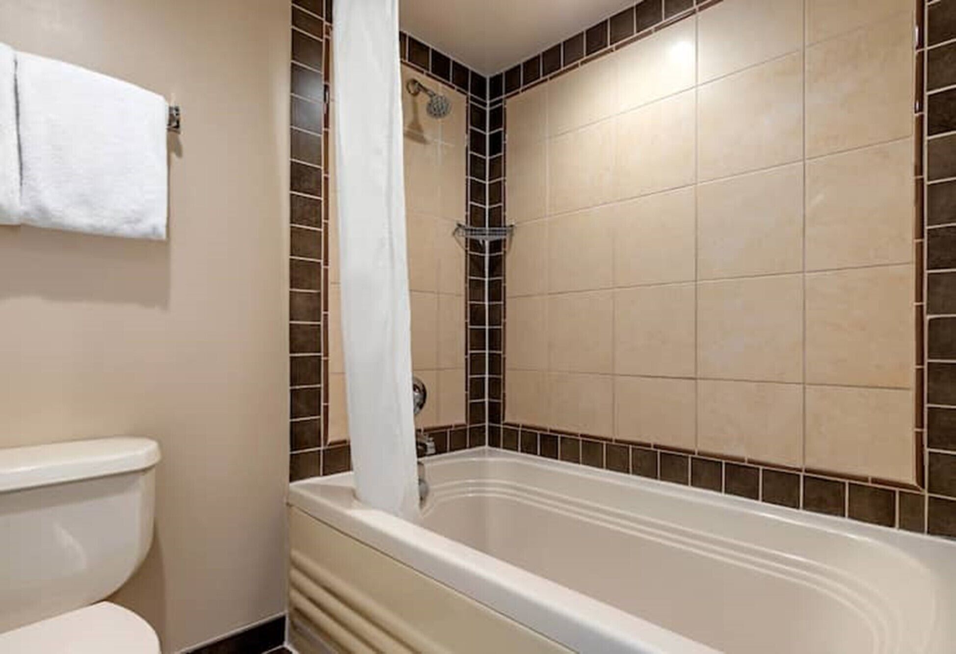 A bathroom with a bathtub, toilet, and tiled walls.
