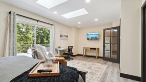 A modern bedroom with a large bed, skylight windows, a desk, and a view of the outdoors. - Emerald in Berkeley Springs, WV (Berkeley Springs)