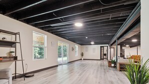 A spacious room with a high ceiling, wooden flooring, and large windows allowing natural light. - Emerald in Berkeley Springs, WV (Berkeley Springs)