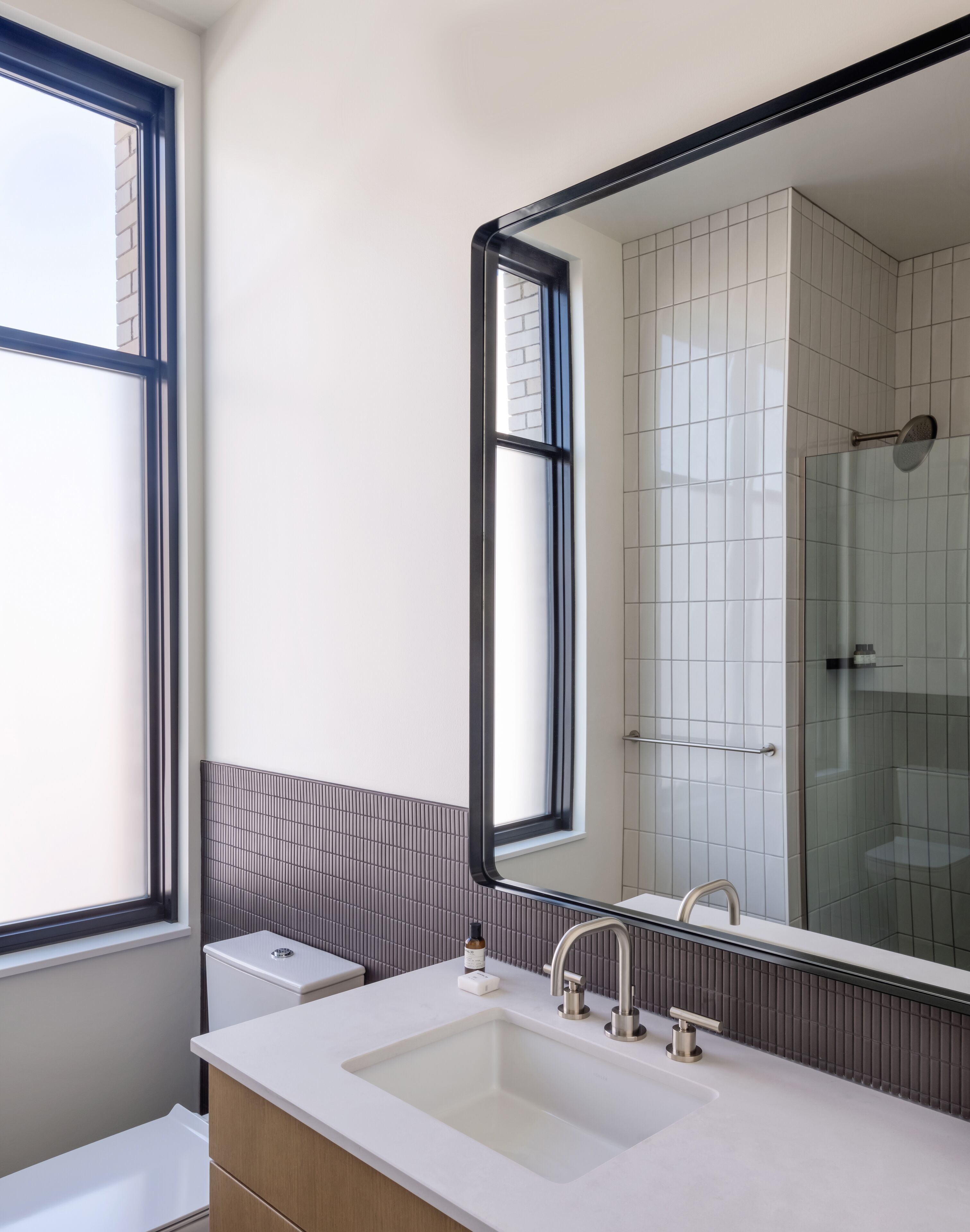 Une salle de bain moderne avec un grand miroir, un lavabo blanc et un espace douche.