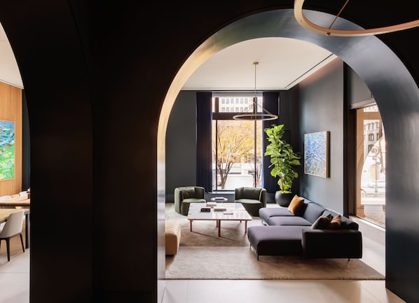 Un salon moderne avec un canapé, une table basse et une grande fenêtre offrant une vue sur la ville.