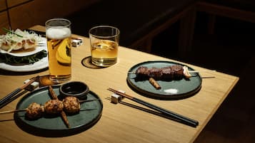 Une table à manger avec des assiettes de nourriture, un verre de bière et un verre de whisky.