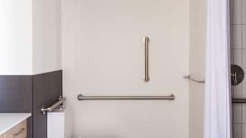 A bathroom with a toilet, a grab bar, a shower curtain, and a tiled floor.